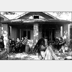 Black and white photograph of people sitting in their porch in New Orleans. Title: 2016 - New Orleans
