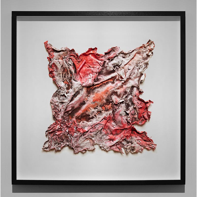 Framed abstract textural work on paper. Mainly red and brown colors. Title: Pompeii Papyrus