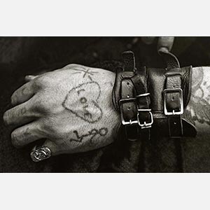 Black and white photograph of a male hand with leather bracelets and a tatoo. Limited edition print. Title: Hells Angels' Tatooed Hand at the Isle of Wight 1970 Festival