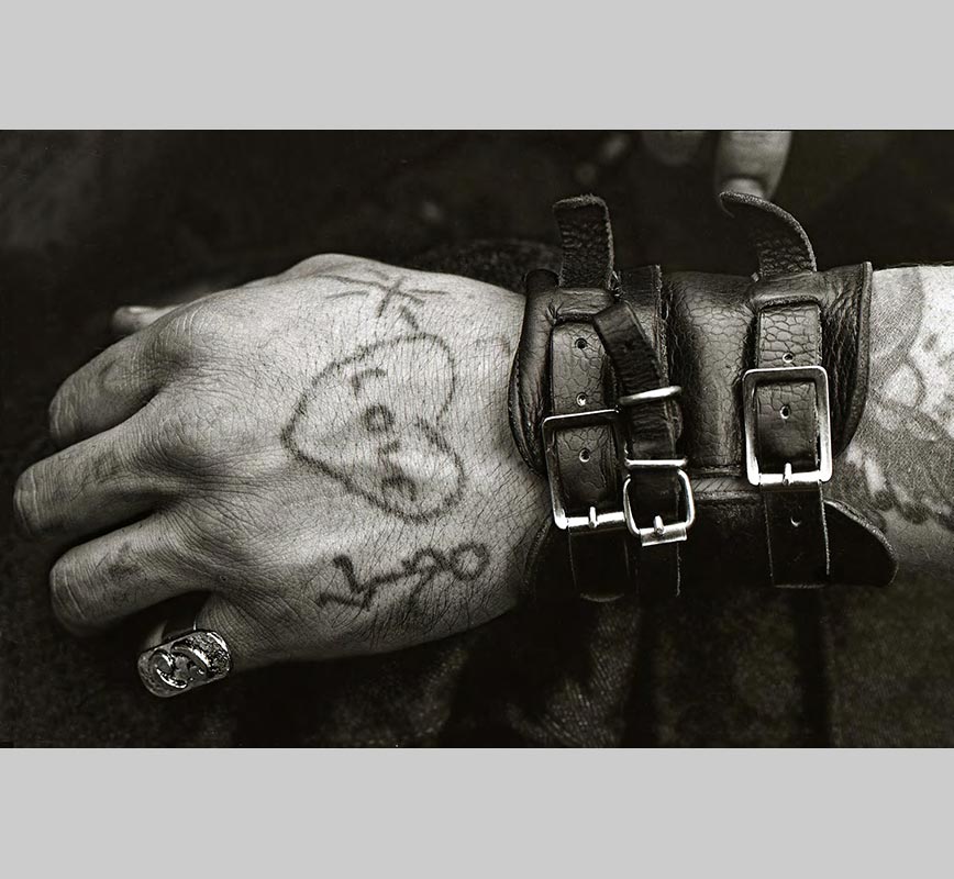 Black and white photograph of a male hand with leather bracelets and a tatoo. Limited edition print. Title: Hells Angels' Tatooed Hand at the Isle of Wight 1970 Festival